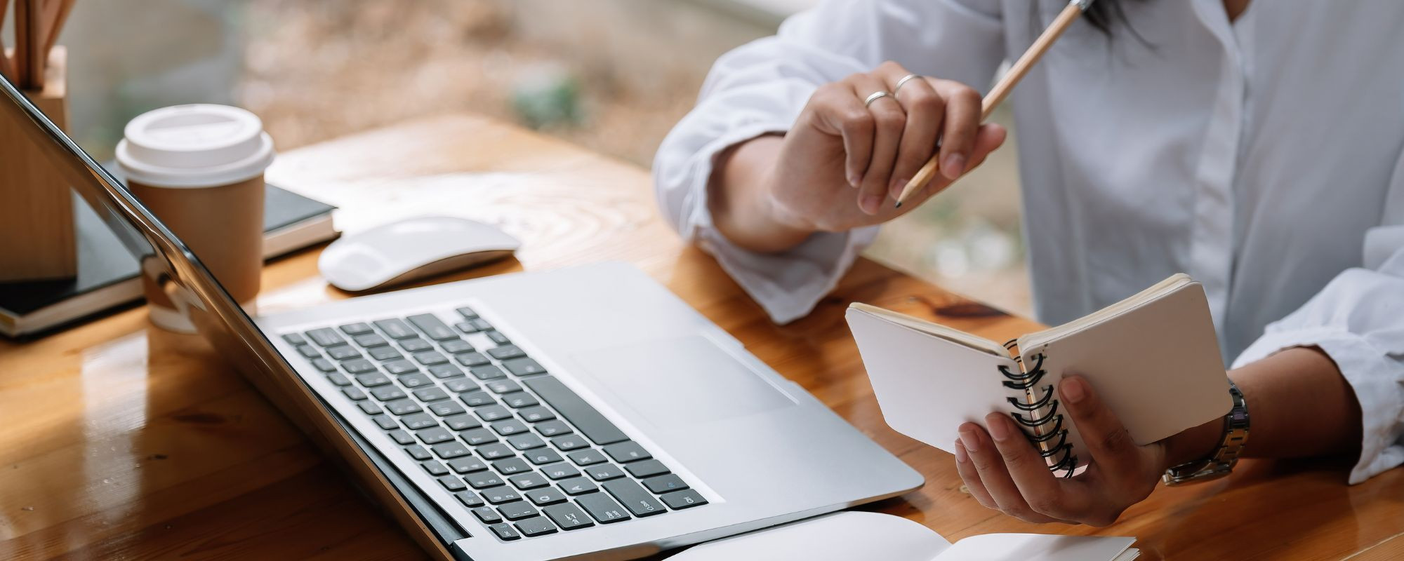 Woman at a desk with her notepad, pencil and laptop